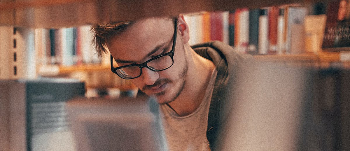 Una persona mirando entre las estanterías de una biblioteca