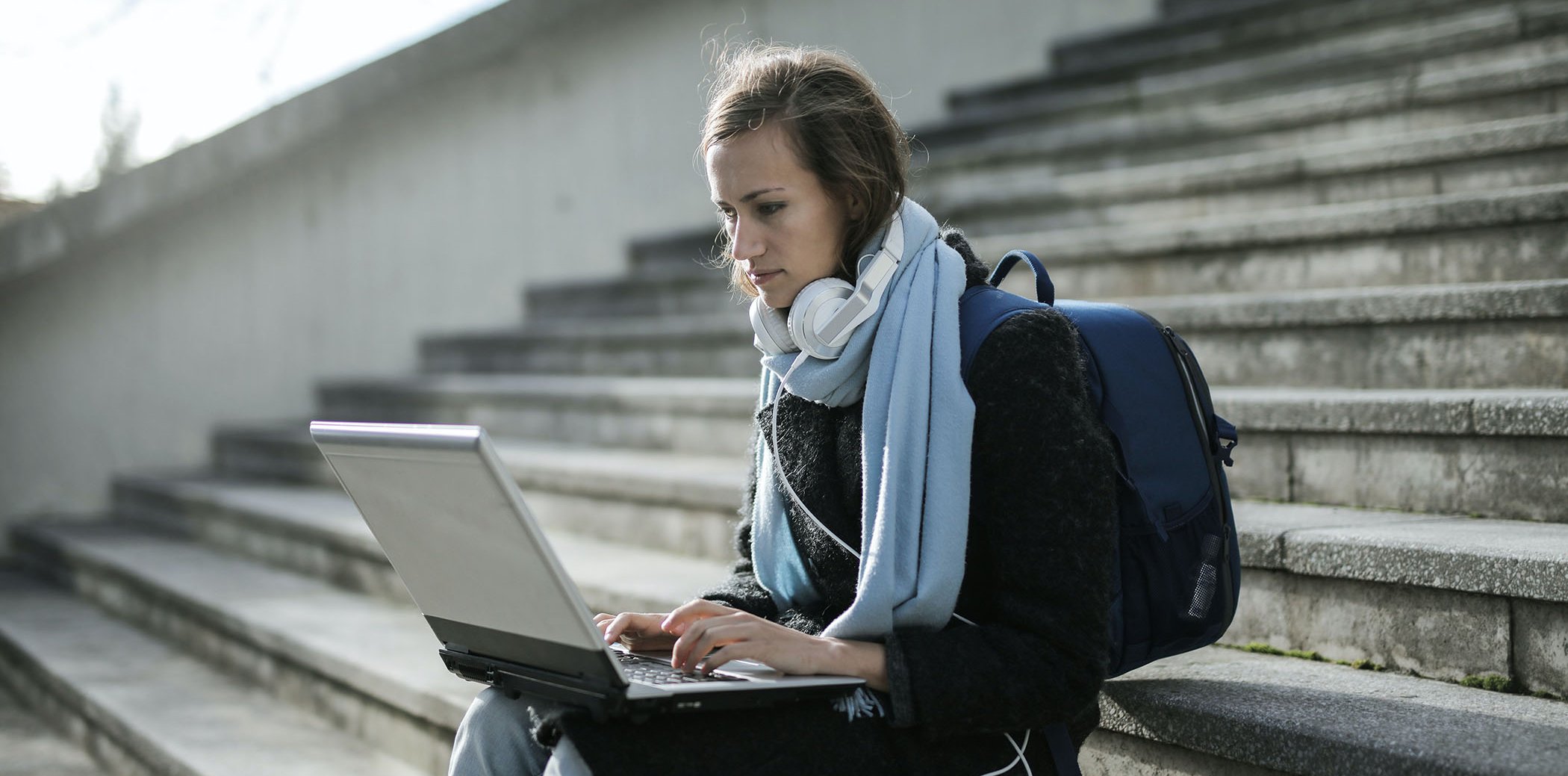 A woman sitting on a stairwell with an open laptop