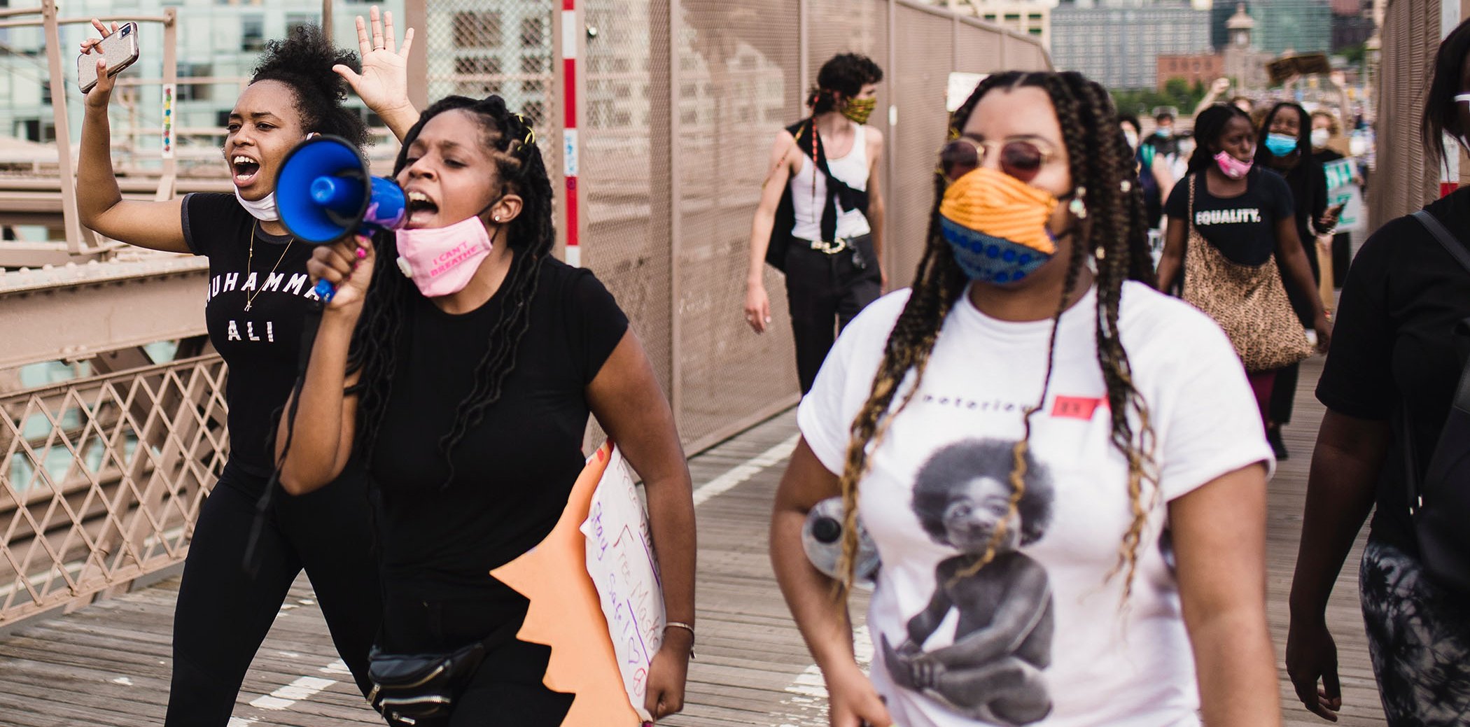 Tres dones joves, una d'elles amb un megàfon, participant en una manifestació