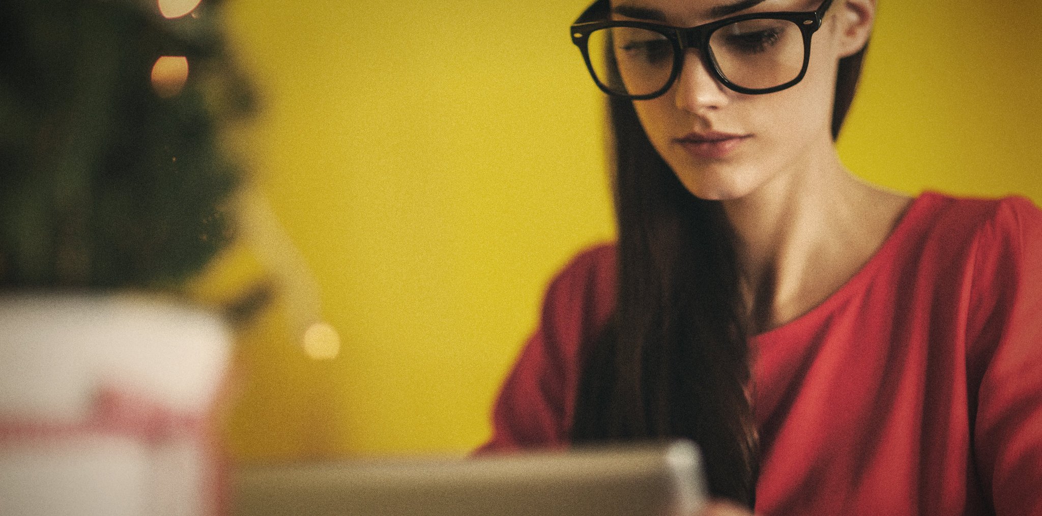 A woman with glasses looking at a tablet