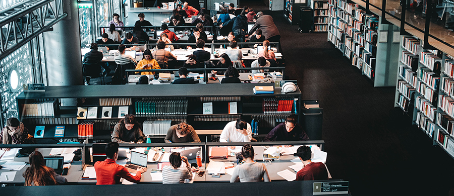 Una secció d'una biblioteca amb taules plenes de persones treballant i estudiant