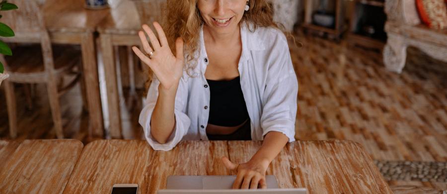 Una mujer saludando delante de una pantalla de ordenador