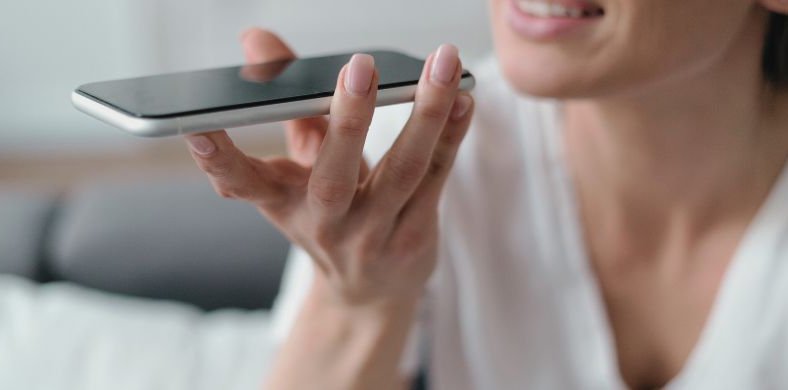 This image shows a woman talking on the phone in hands-free mode, with a relaxed expression and a slight smile. It conveys a sense of close and spontaneous conversation.