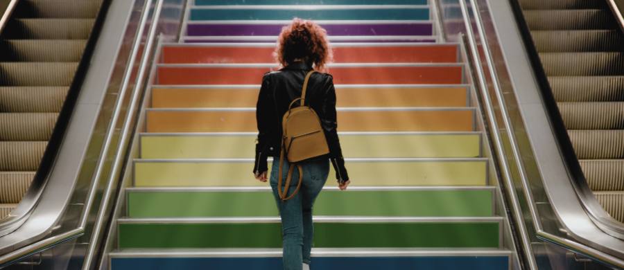 Una persona pujant escales amb els colors de la bandera LGTB